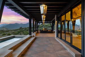 Expansive outdoor patio with a built-in spa, pergola, and an outdoor kitchen featuring a grill and cabinetry