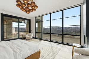 Expansive floor-to-ceiling windows featuring black framing, a modern multi-pendant chandelier with amber glass shades, light wood-finish flooring, and a contemporary linear fireplace