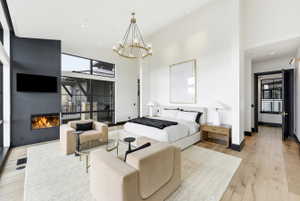 Expansive room featuring light wood-finish flooring, a contemporary fireplace, and a large window wall
