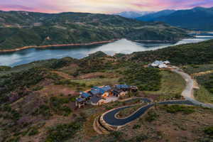 Hillside property featuring a winding paved driveway and a multi-level residence with a dark roof