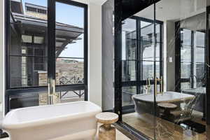Freestanding soaking tub positioned before expansive black-framed windows
