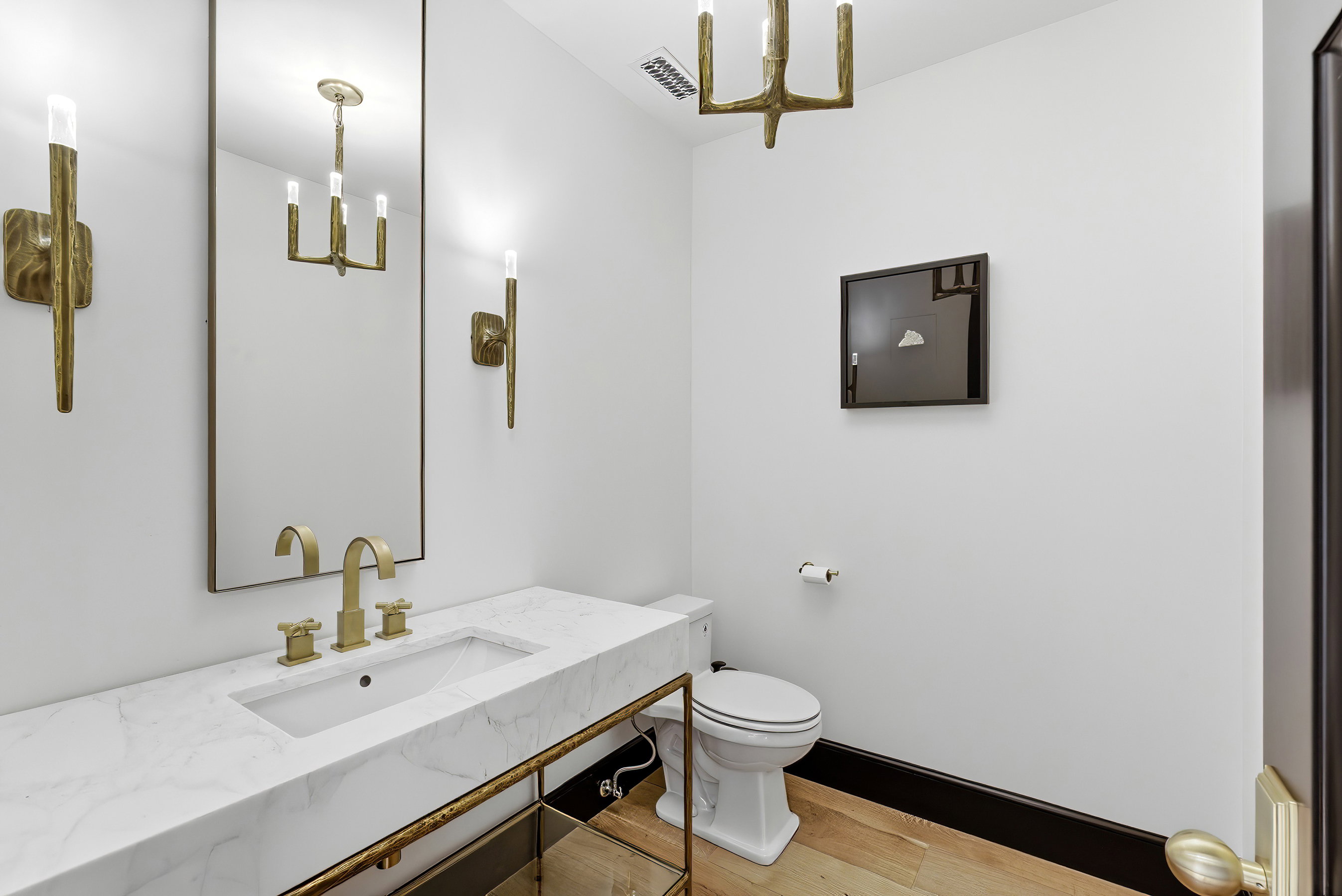 Modern powder room featuring a rectangular under-mount sink, white countertop, and gold-finish fixtures