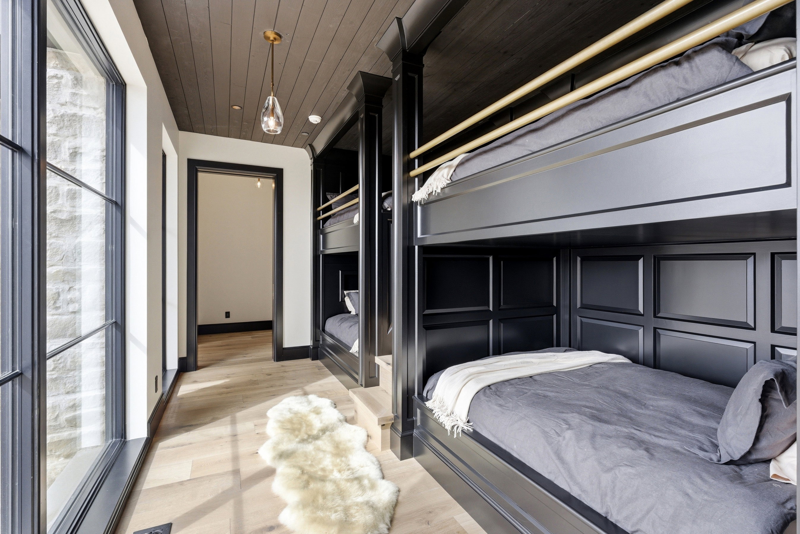 Built-in bunk beds with paneled detailing, light wood-finish flooring, and shiplap ceiling