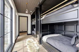 Built-in bunk beds with paneled detailing, light wood-finish flooring, and shiplap ceiling