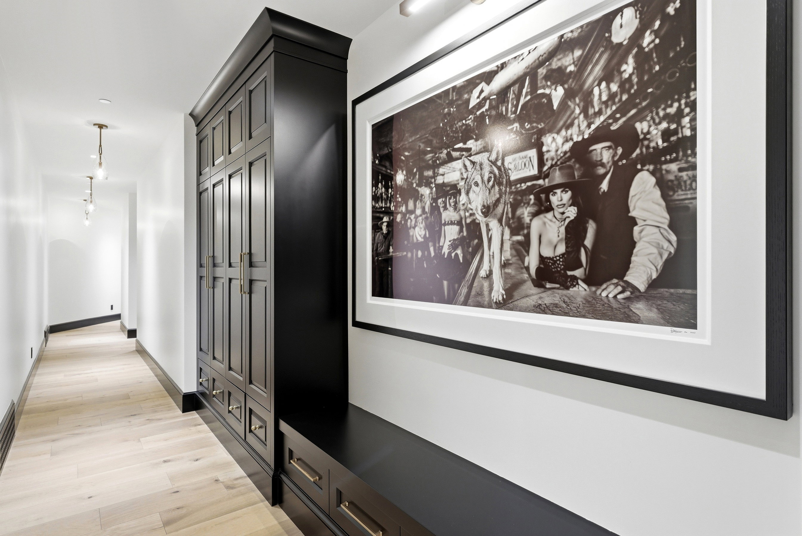 Hallway with light wood-finish flooring, white walls, and dark baseboards
