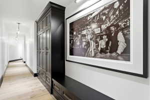 Hallway with light wood-finish flooring, white walls, and dark baseboards