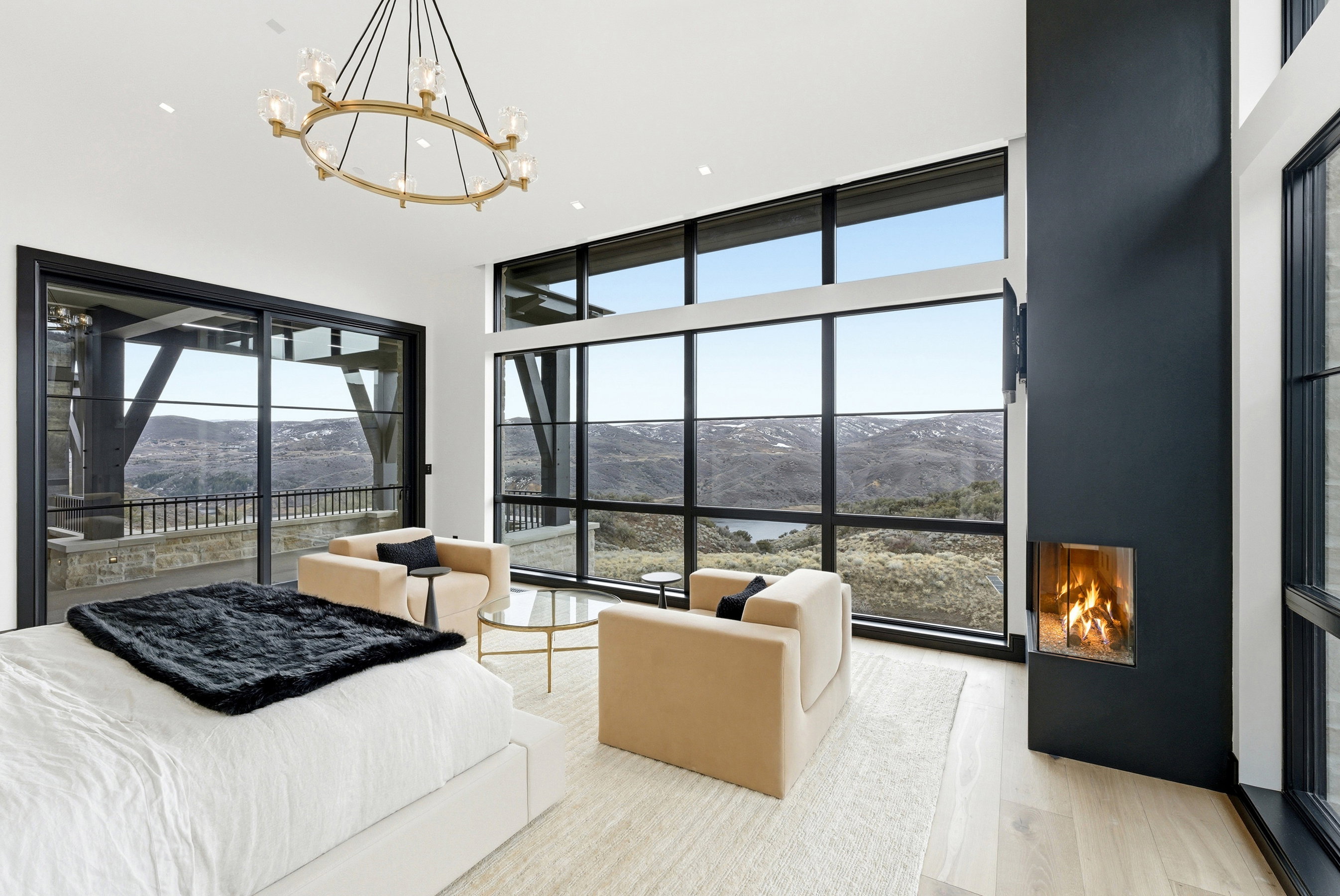 Spacious room featuring floor-to-ceiling windows, a built-in fireplace, a large sliding glass door, light wood-finish flooring, and a contemporary chandelier