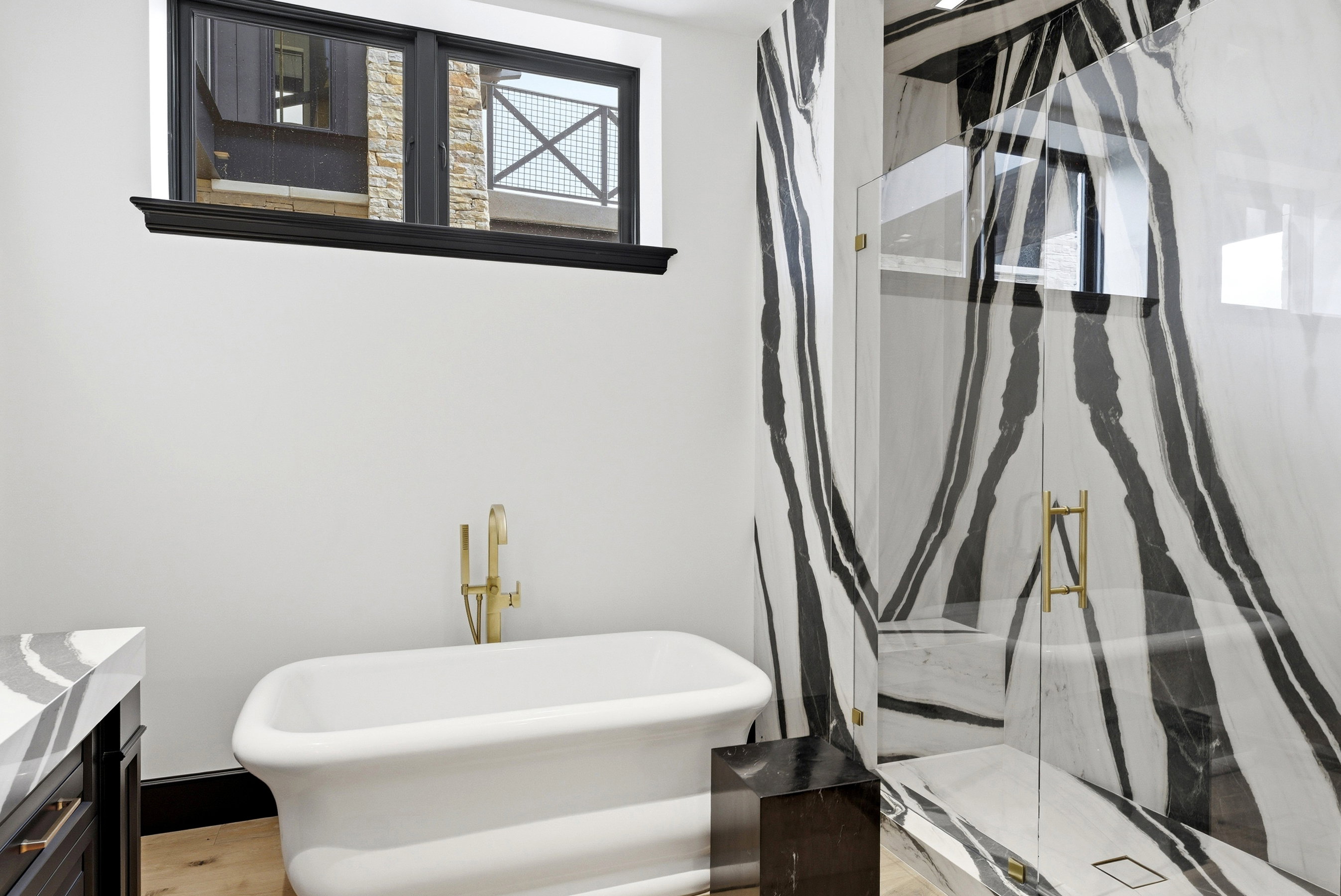 Freestanding white soaking tub with a brass floor-mounted faucet