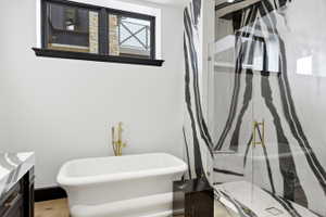 Freestanding white soaking tub with a brass floor-mounted faucet