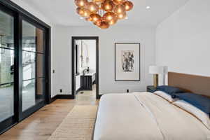 Bright bedroom featuring wood-finish flooring, a contemporary chandelier, and a recessed ceiling light
