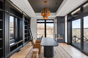Room featuring built-in dark wood cabinetry with a rolling ladder, a modern linear fireplace, and wood-finish flooring