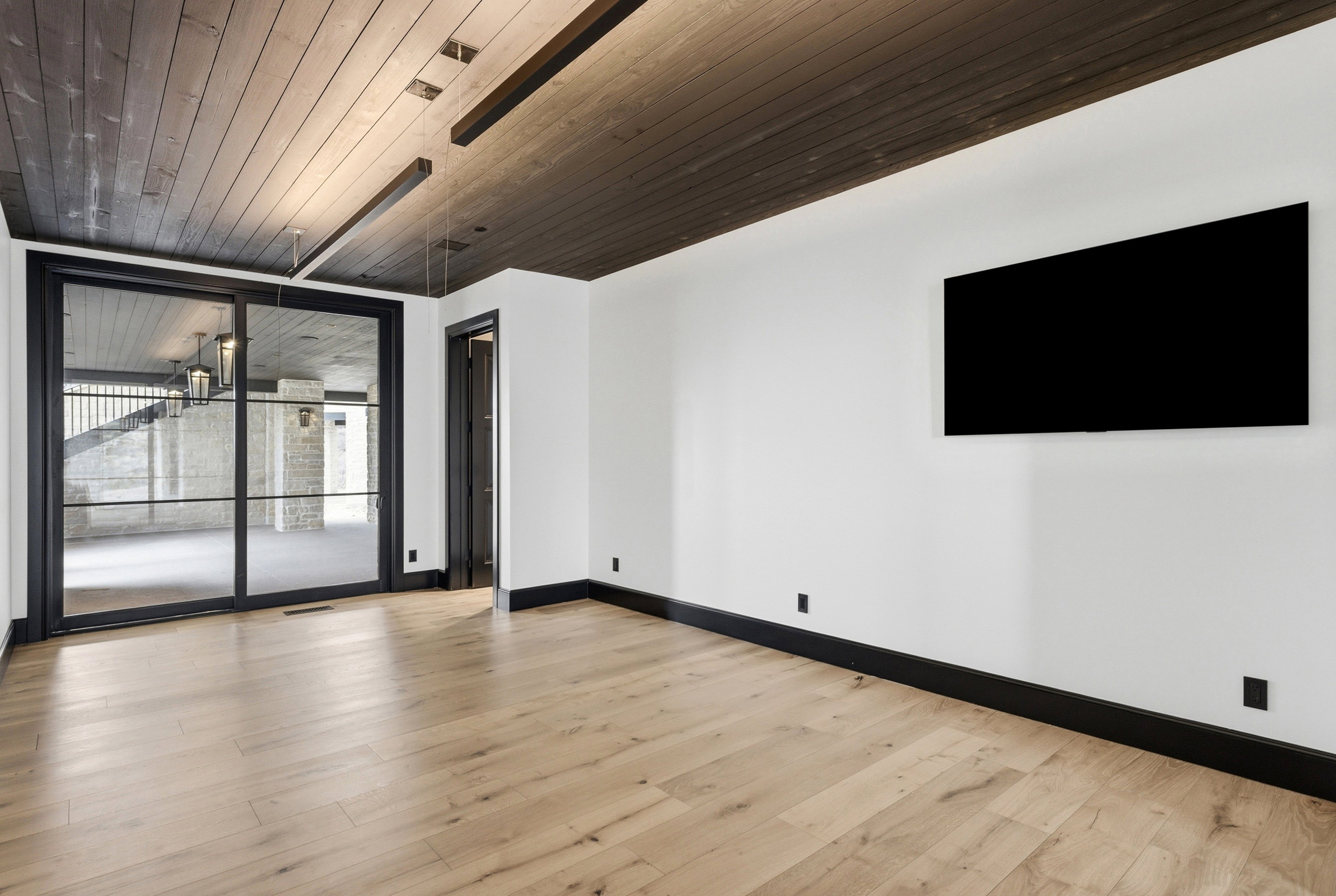 Room with light wood-finish flooring, white walls, and dark trim