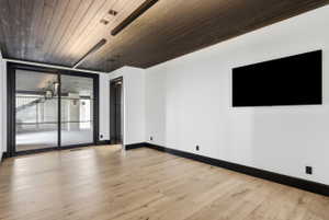 Room with light wood-finish flooring, white walls, and dark trim