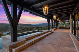 Expansive outdoor patio with a built-in outdoor kitchen, an infinity-edge pool, and a pergola with integrated lighting