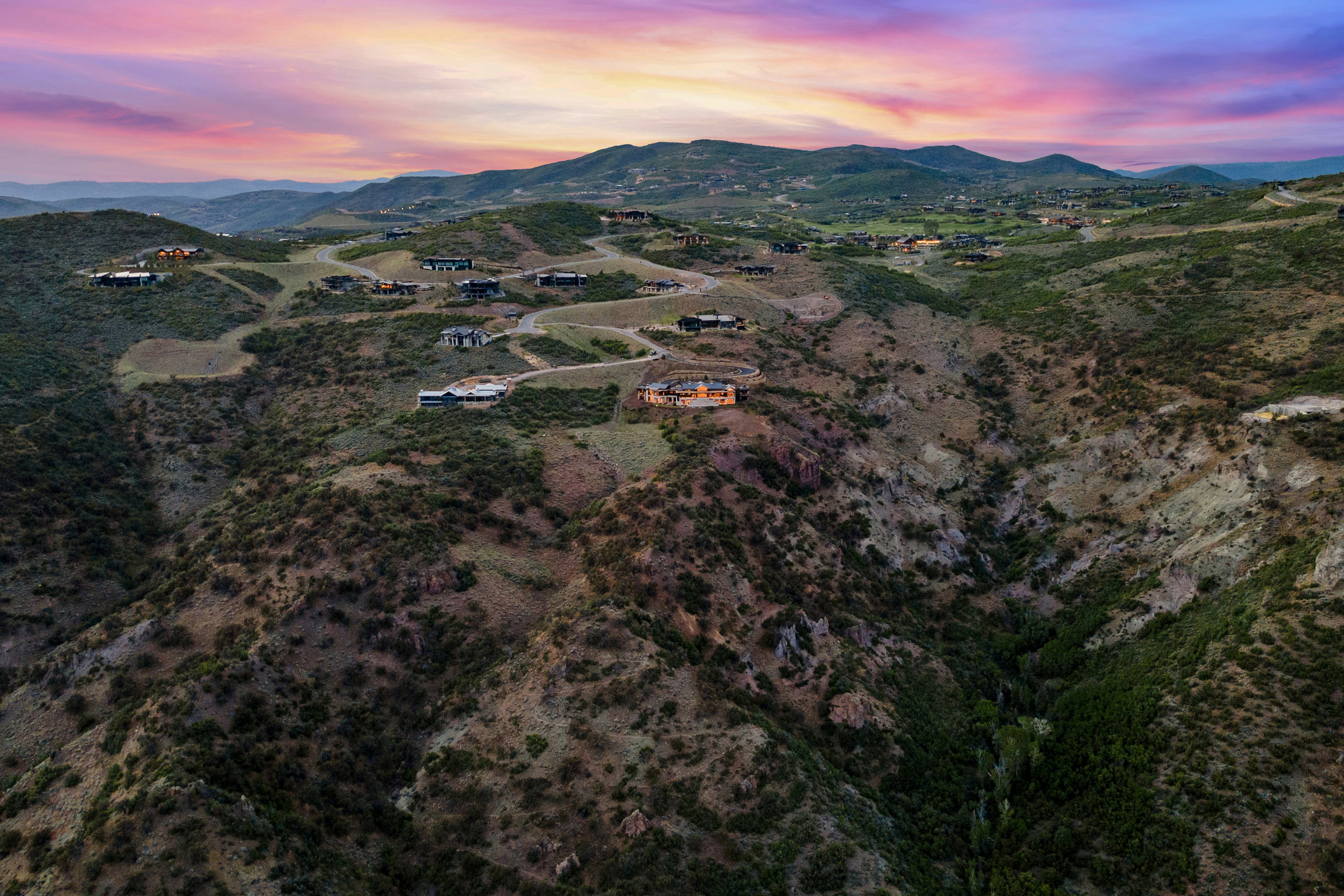 Expansive mountainous terrain featuring scattered residential properties, winding roadways, and a prominent valley