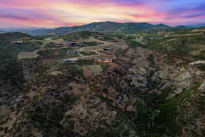 Expansive mountainous terrain featuring scattered residential properties, winding roadways, and a prominent valley