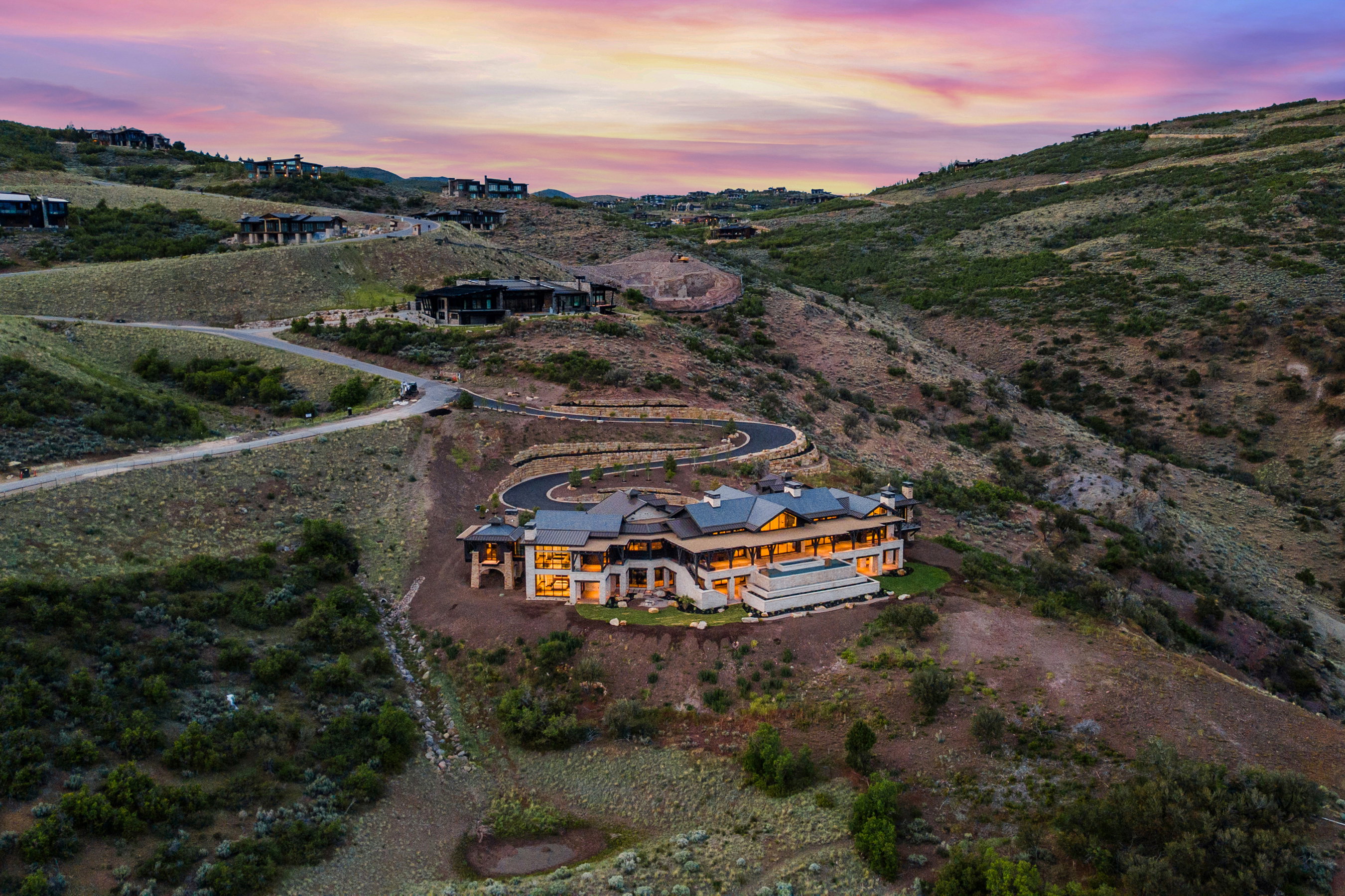 Hillside estate featuring a multi-level architectural design, a winding driveway, and a retaining wall
