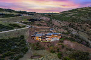 Hillside estate featuring a multi-level architectural design, a winding driveway, and a retaining wall