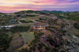 Expansive hillside property featuring a multi-level residence with exterior lighting, a paved driveway, and established landscaping