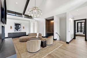 Spacious room featuring vaulted ceilings with exposed beams, wood-finish flooring, and a built-in wet bar with dark cabinetry