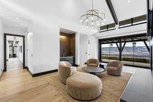 Spacious interior featuring a vaulted ceiling with exposed beams, wood-finish flooring, and a contemporary chandelier