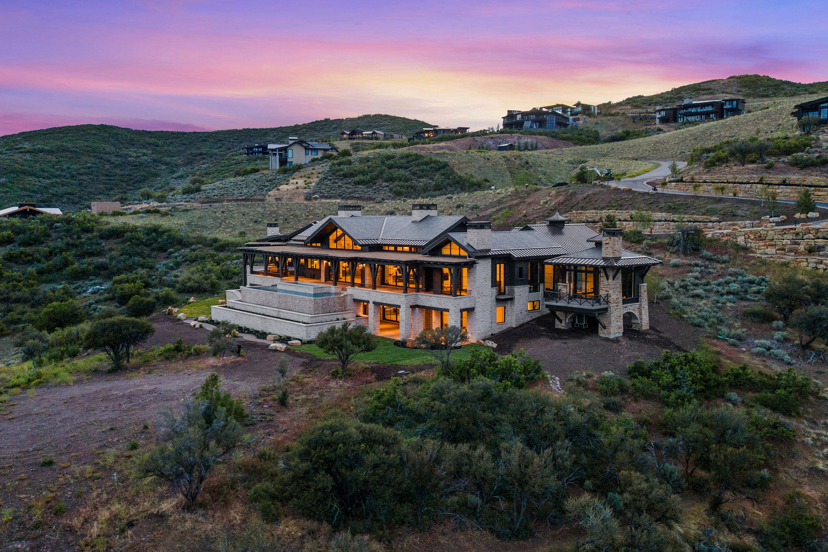 Expansive hillside property featuring a stone and timber facade, multiple covered patios, an infinity-edge pool, and a multi-level architectural design