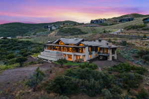 Expansive hillside property featuring a stone and timber facade, multiple covered patios, an infinity-edge pool, and a multi-level architectural design