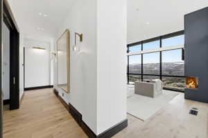 Open concept living space featuring wide plank wood-finish flooring, a contemporary built-in fireplace, and full-height windows with black frames