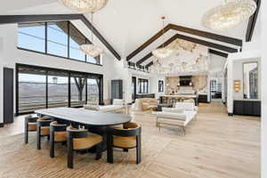 Expansive open-concept living area featuring a vaulted ceiling with exposed beams, wood-finish flooring, and large sliding glass doors