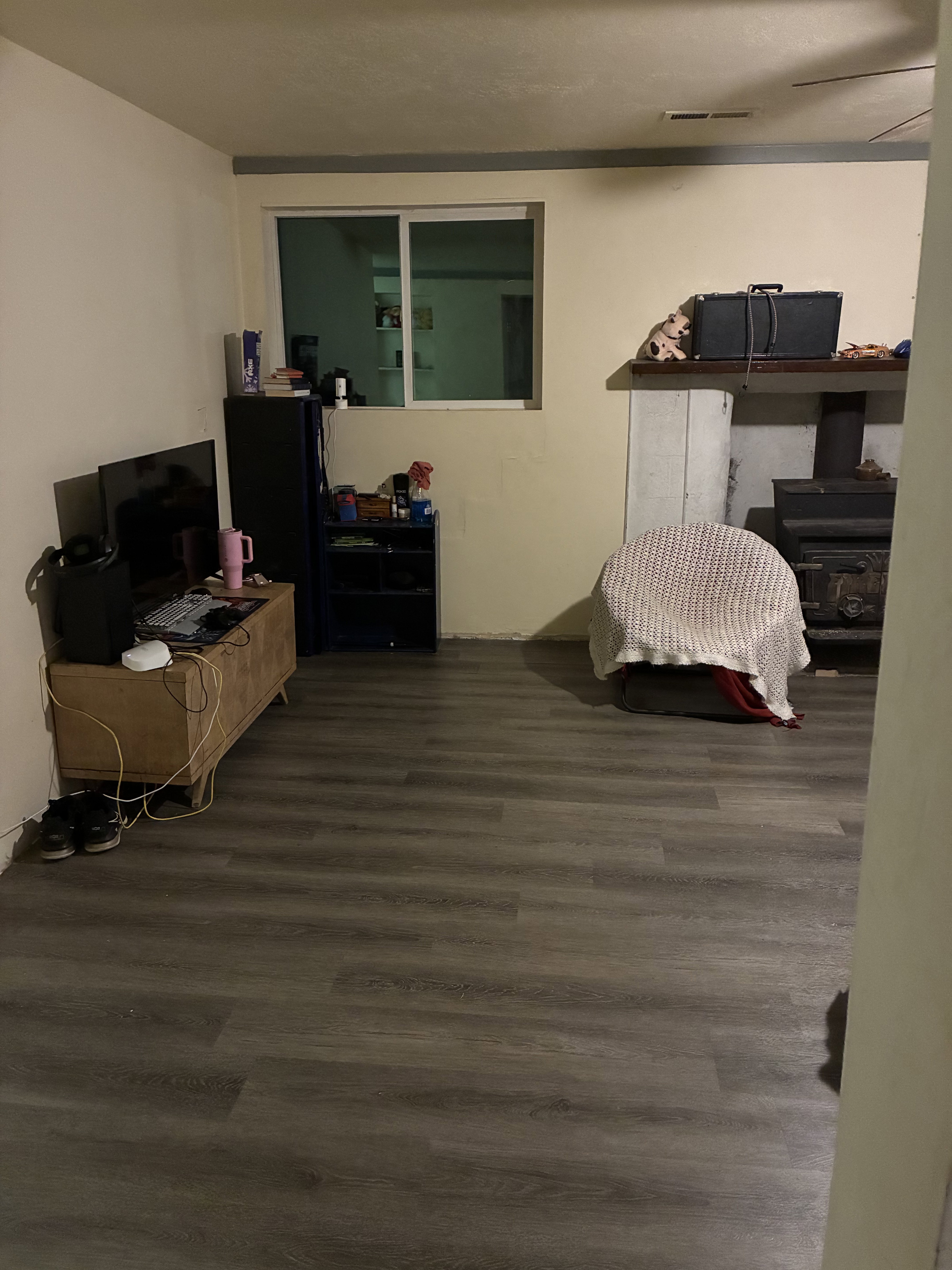 Spacious room featuring wood-finish flooring, a sliding window, and neutral wall paint