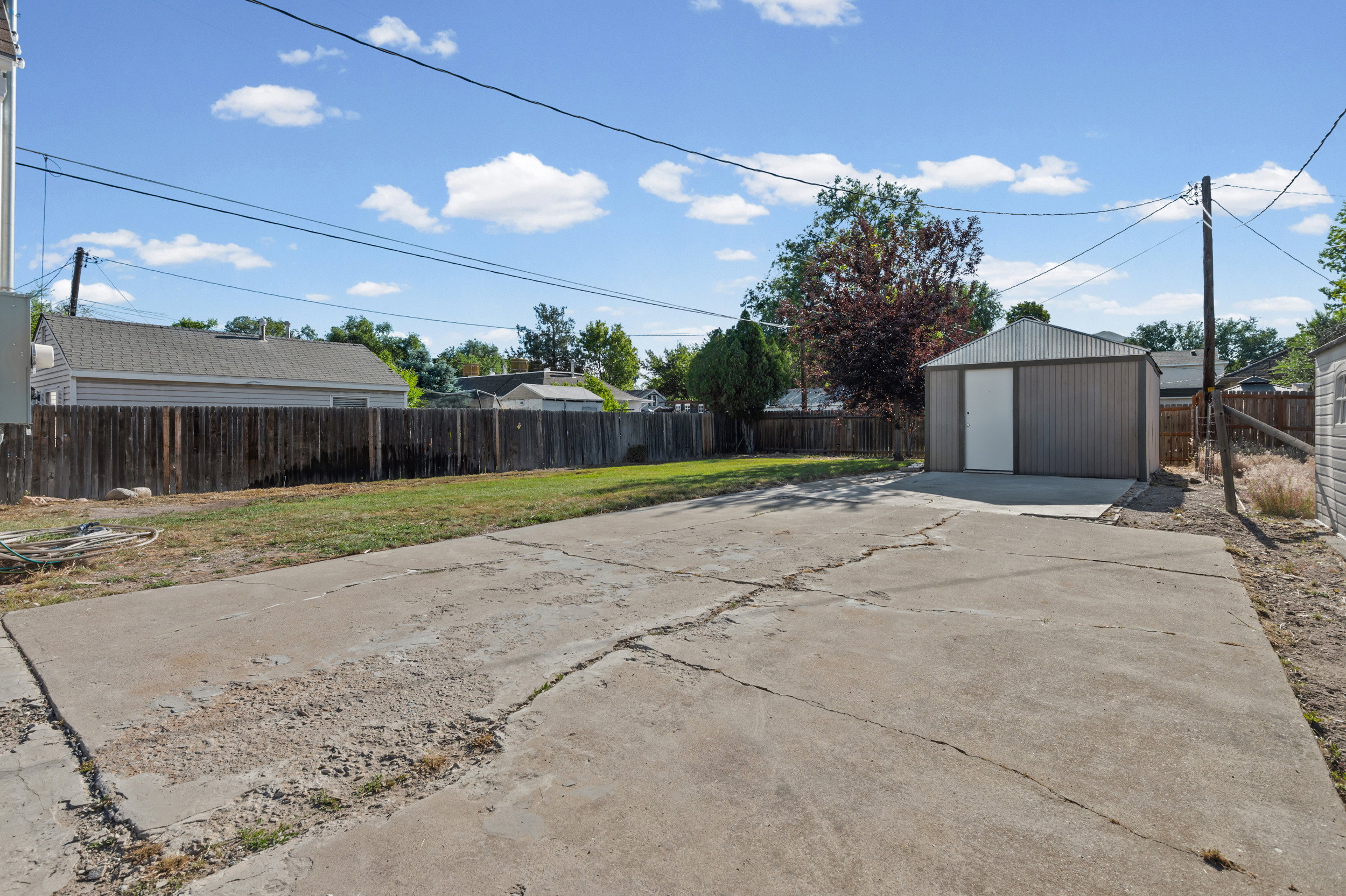 Expansive concrete pad leading to a detached metal storage shed with a single entry door