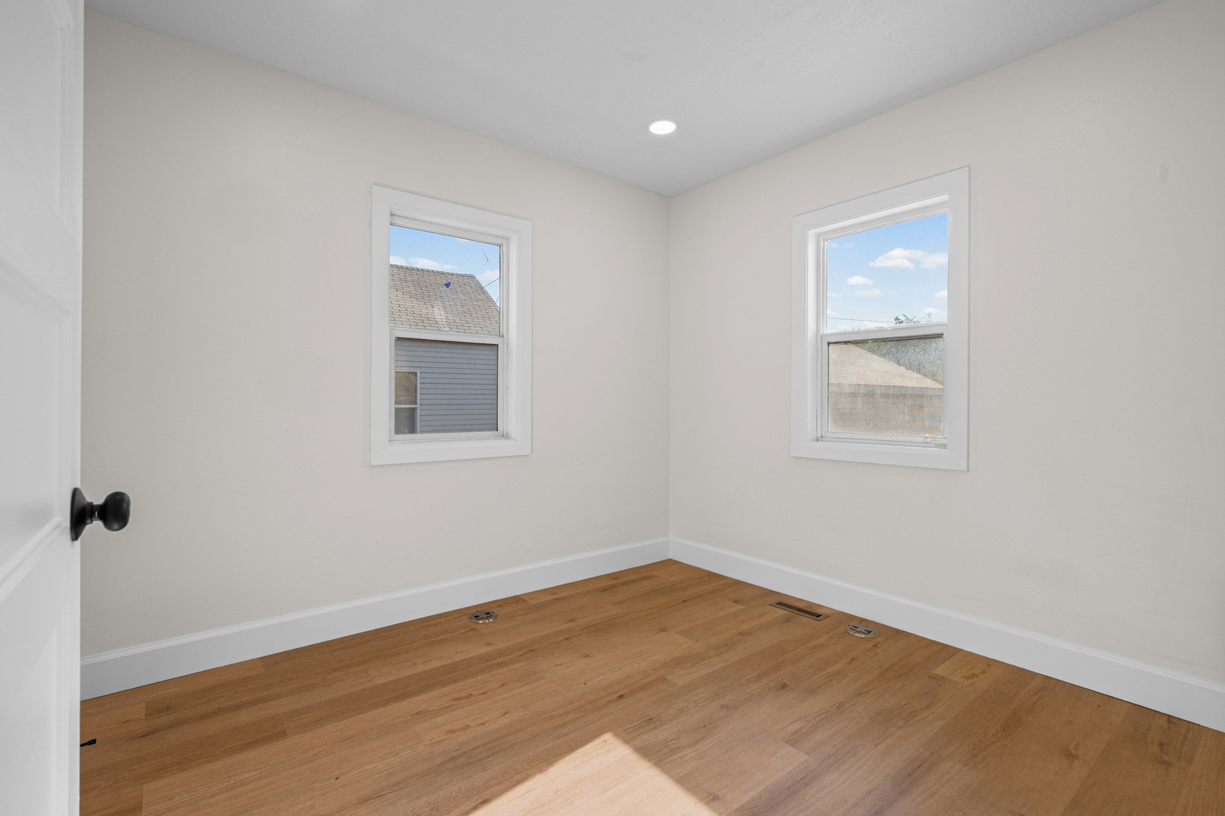 Neutral wall tones with wood-finish flooring, two windows, recessed lighting, and white baseboards