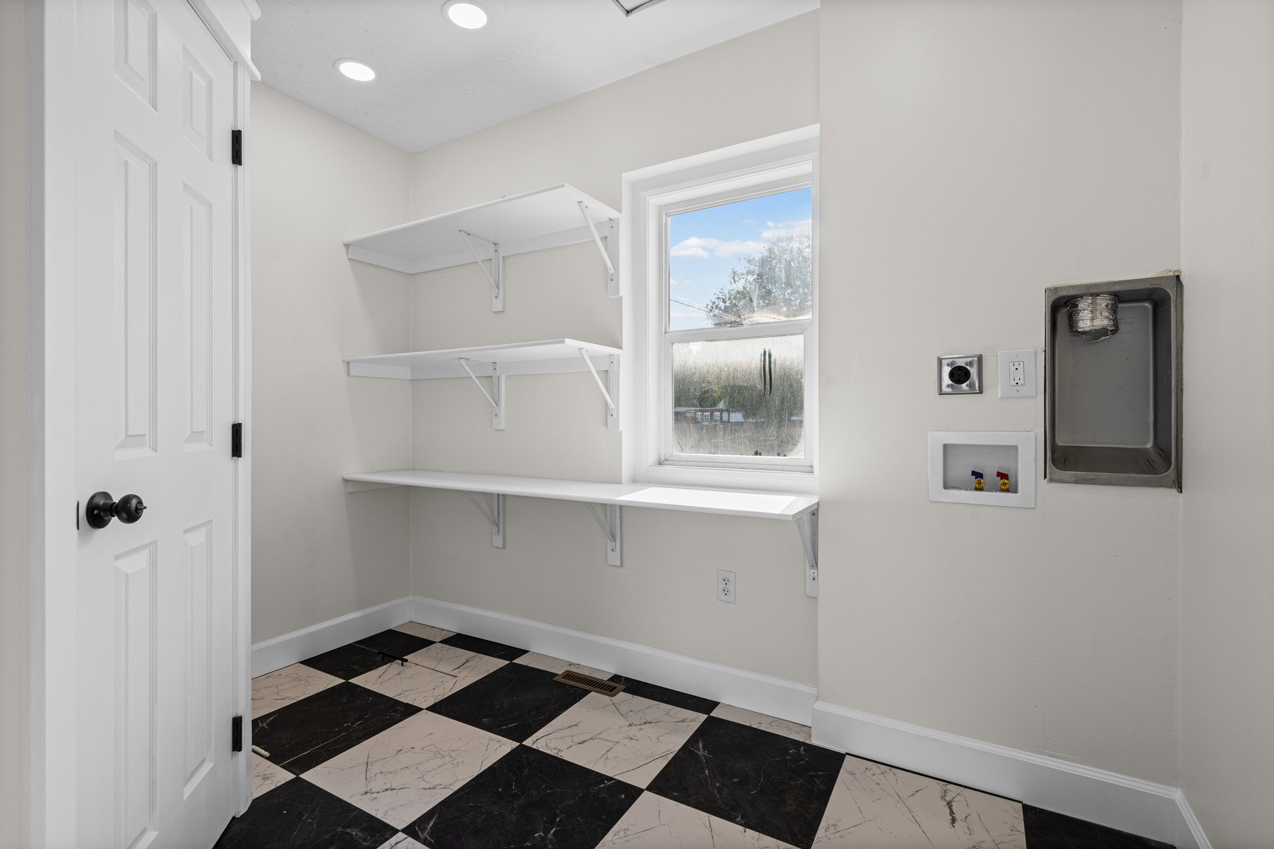 Laundry area featuring checkerboard flooring, a window, recessed lighting, and wall-mounted shelving