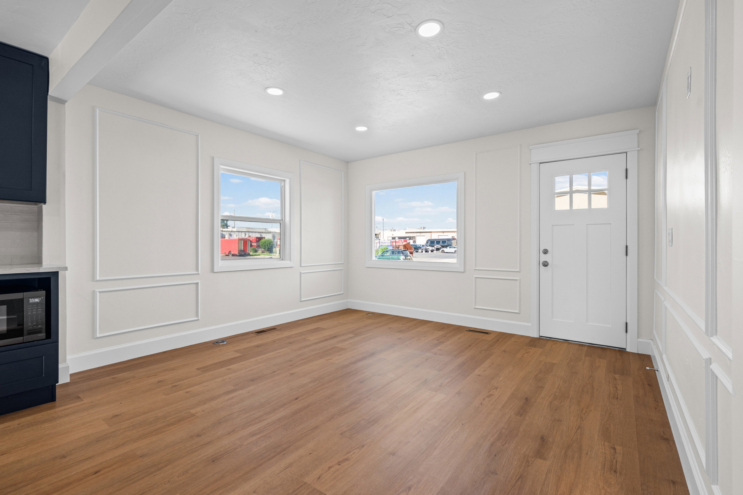 Open-concept living space with wood-finish flooring, recessed lighting, and decorative wall molding