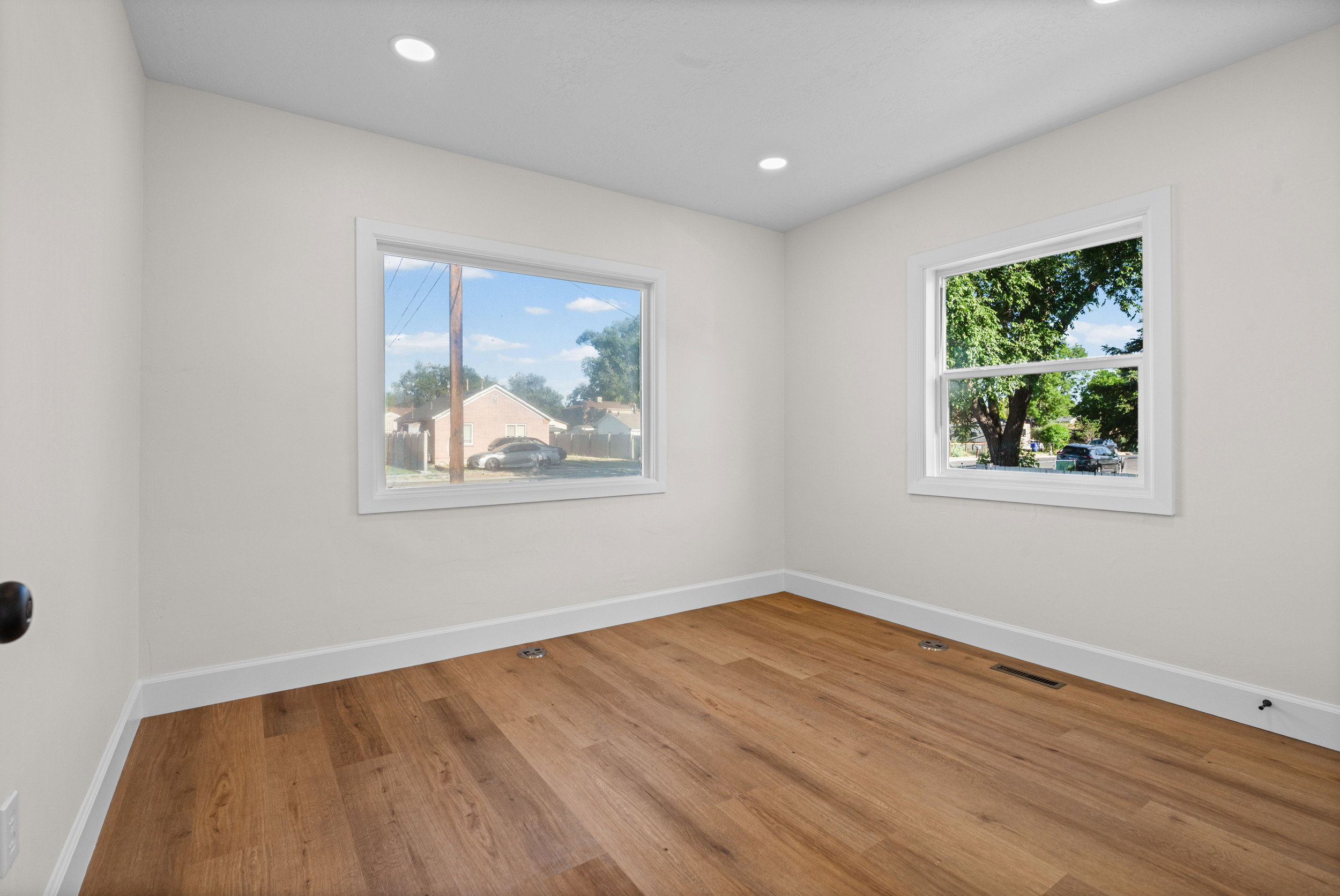 Room featuring wood-finish flooring, recessed lighting, and two windows with white trim