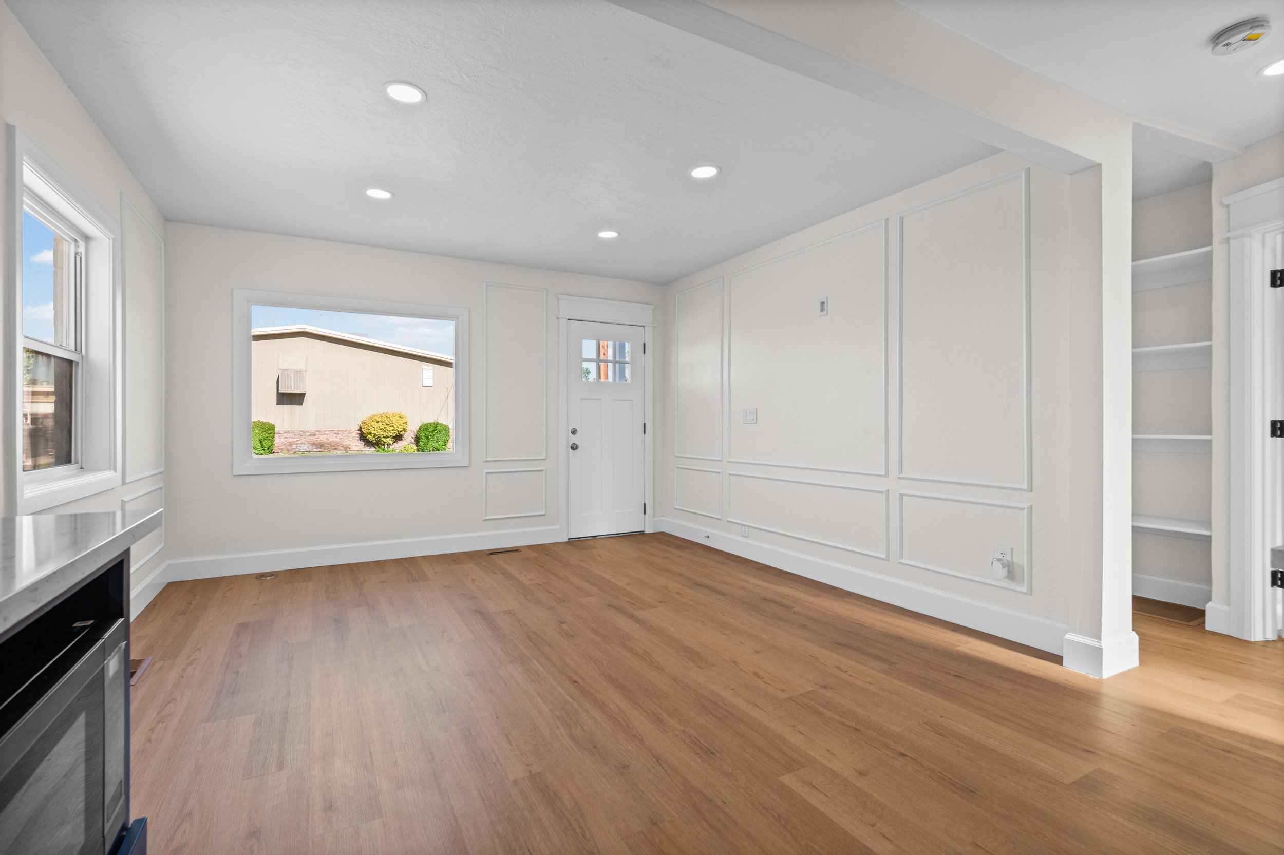 Spacious room featuring wood-finish flooring, recessed lighting, and decorative wall paneling