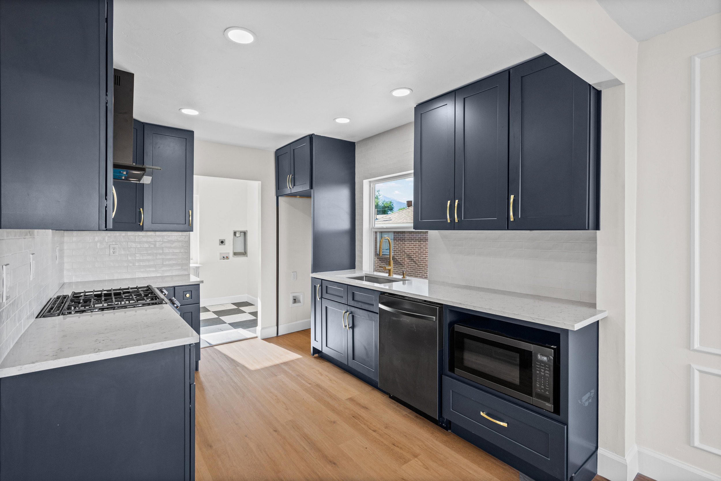 Modern kitchen featuring shaker-style cabinetry, light wood-finish flooring, white countertops, and recessed lighting