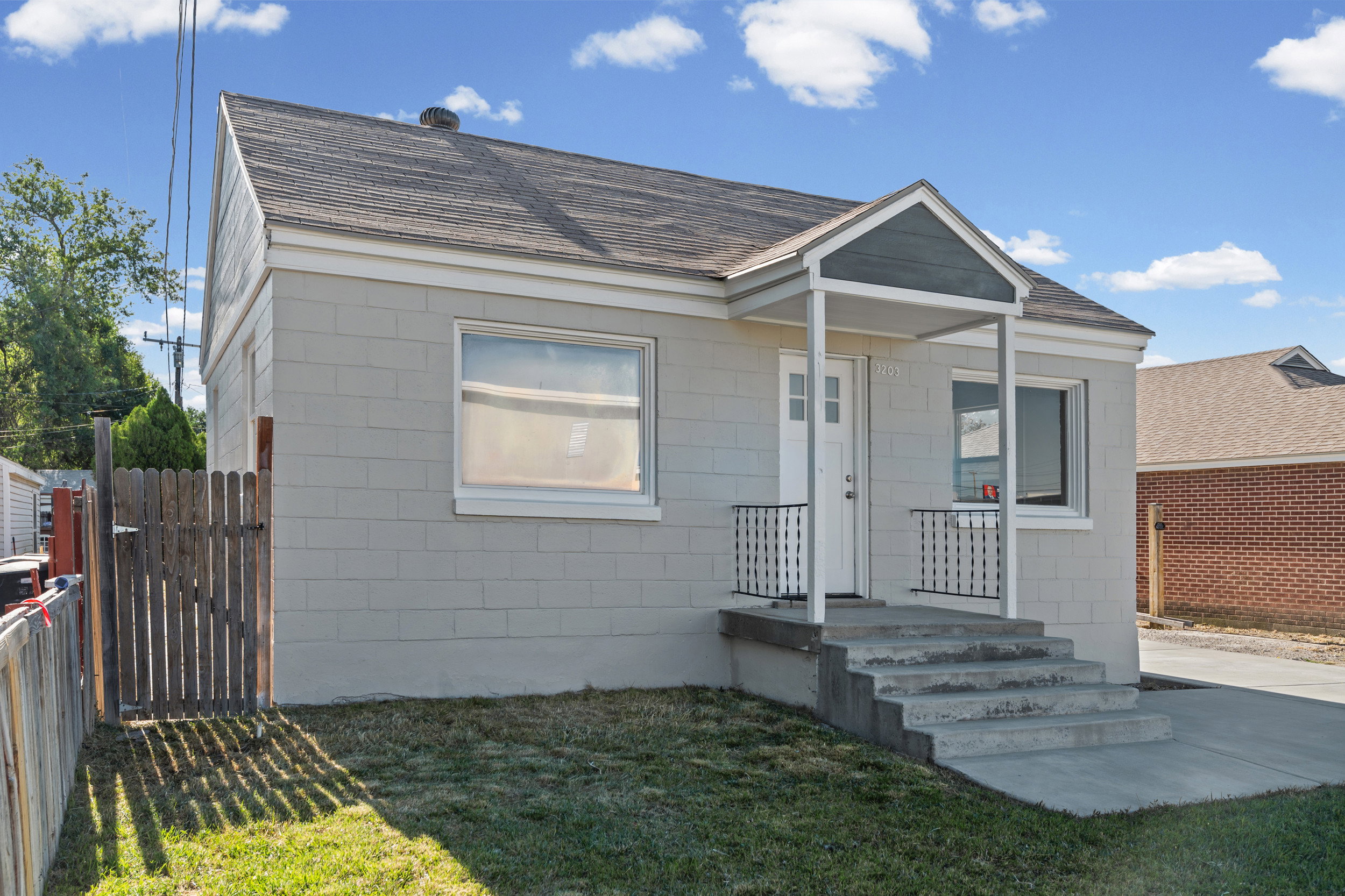 Contemporary exterior featuring light gray block siding and a covered entry