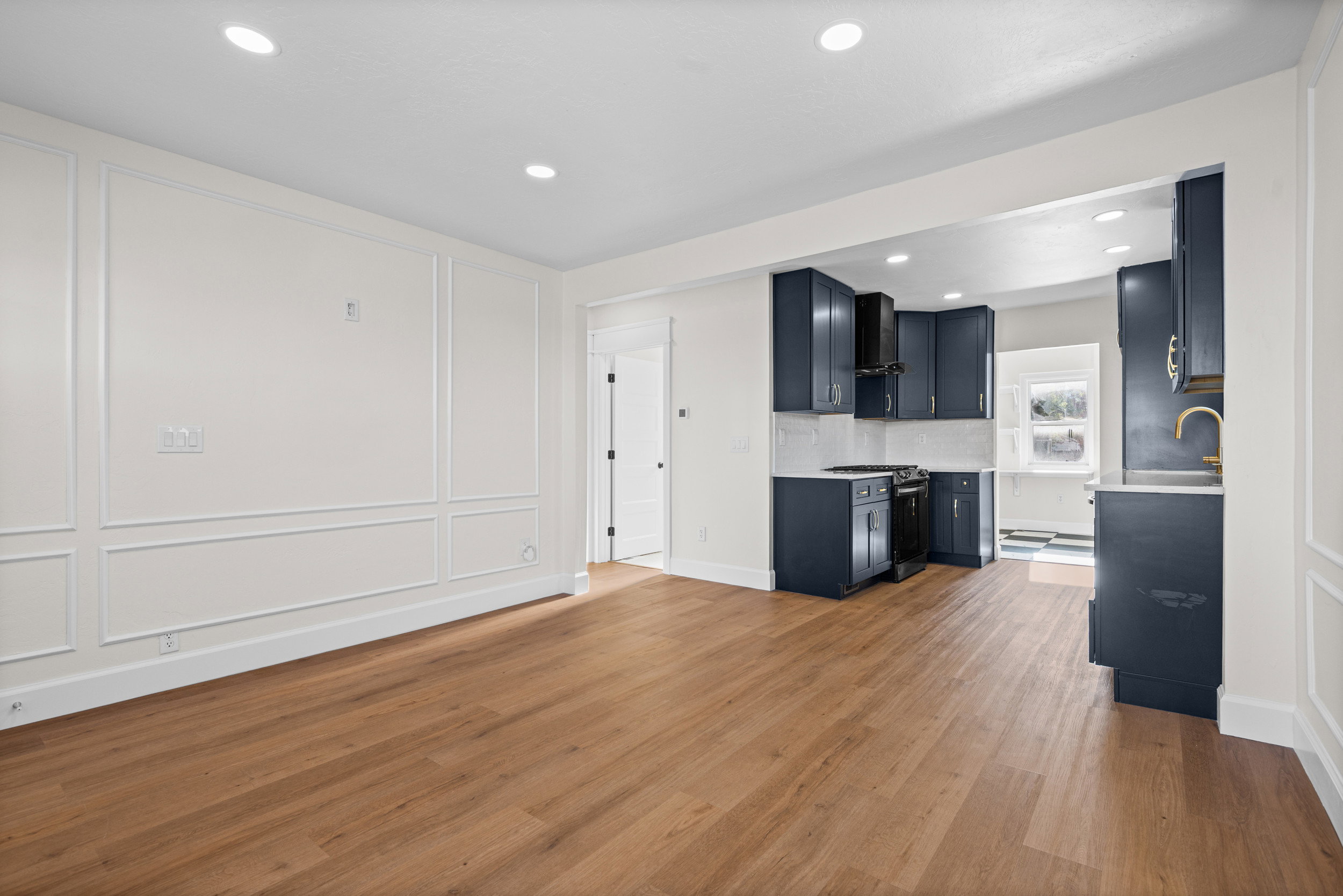 Open-concept living space with wood-finish flooring, recessed lighting, and decorative wall molding