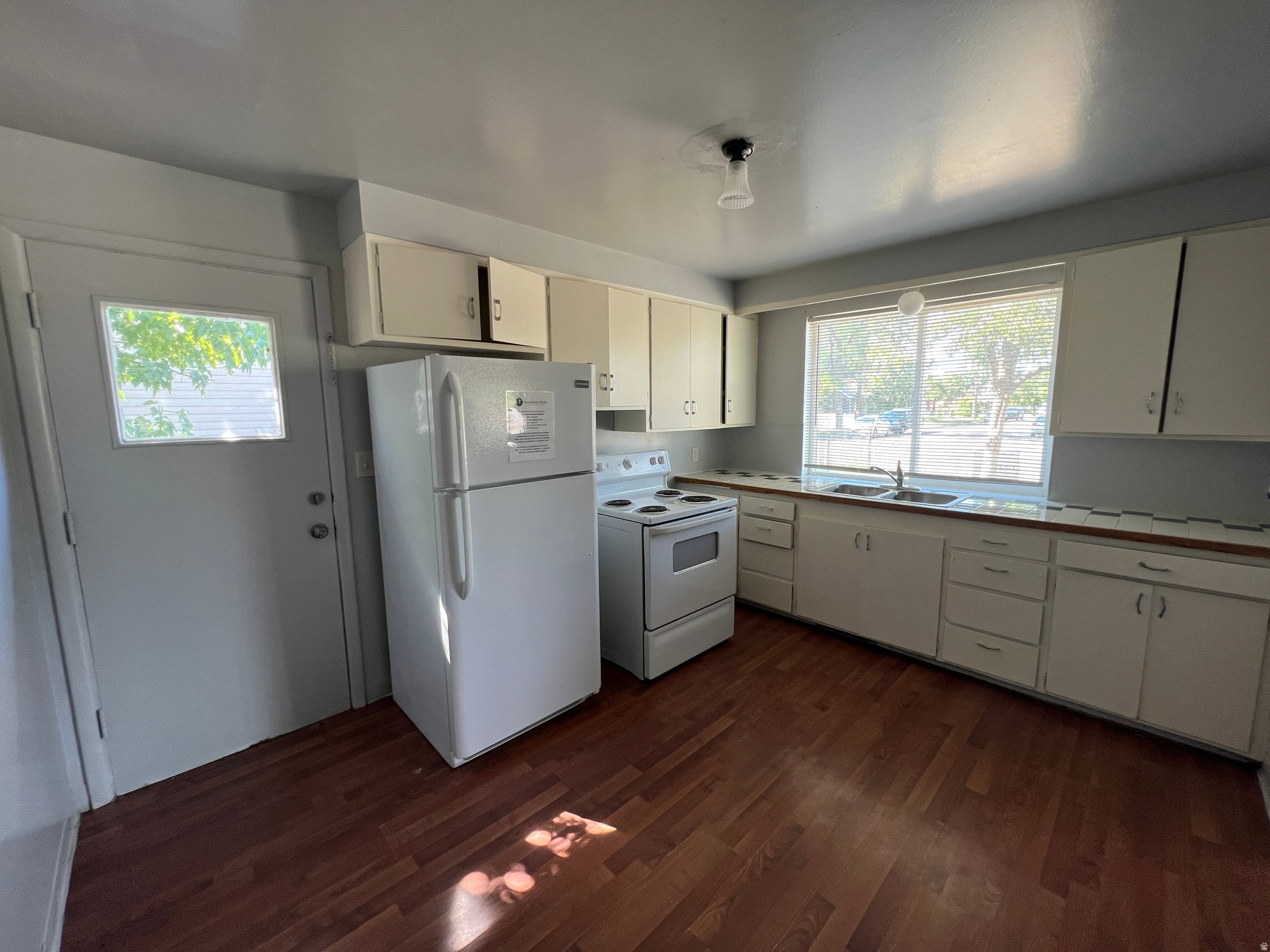 Functional kitchen featuring wood-finish flooring, white cabinetry, and a double-basin sink