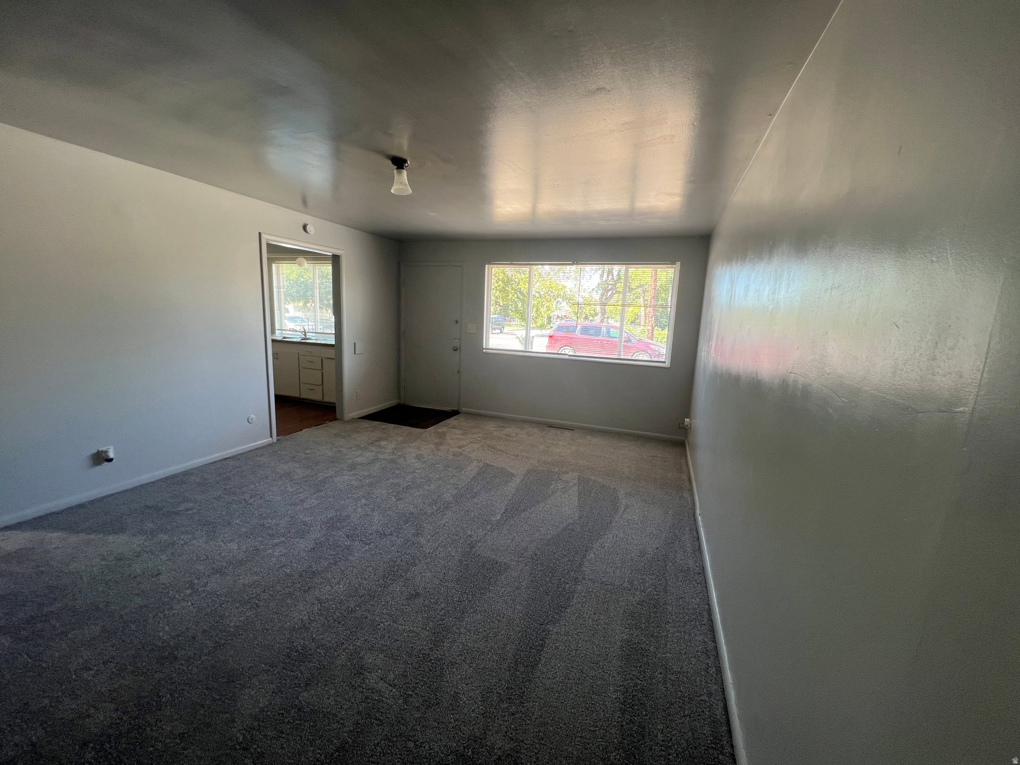 Spacious room featuring neutral grey carpeting and light-colored walls