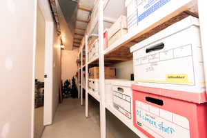 Utility storage area featuring exposed ductwork and open shelving with wood-finish tops