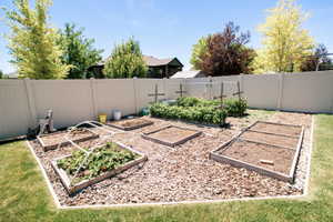 Expansive backyard garden area featuring multiple raised beds and wood chip ground cover