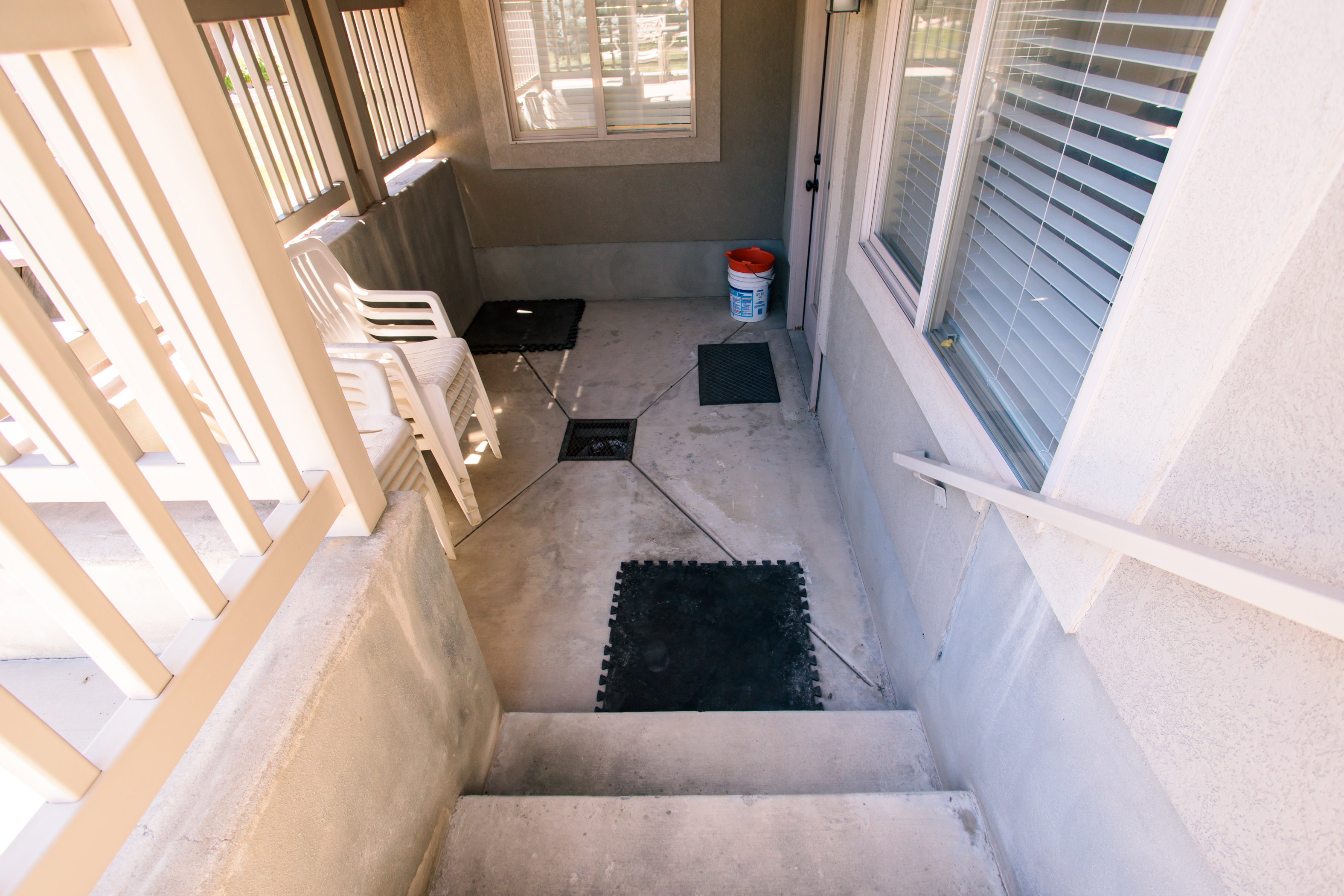 Concrete patio with a decorative stamped pattern, featuring a white railing and exterior stairs. Rear Basement entrance.