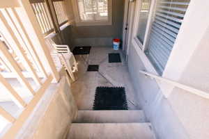 Concrete patio with a decorative stamped pattern, featuring a white railing and exterior stairs. Rear Basement entrance.