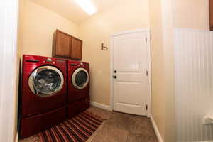 Laundry area featuring tile flooring, a wood-finish wall cabinet, and beadboard wainscoting