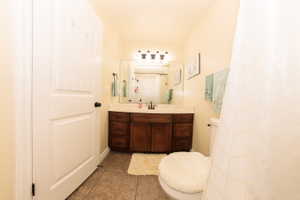 Bathroom featuring a wood-finish vanity with a light-toned countertop, a rectangular mirror, and a four-light fixture
