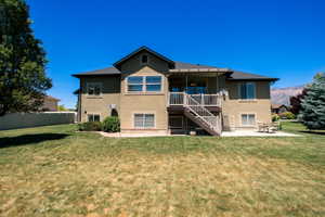 Rear exterior featuring a multi-level deck, ground-level patio, mature landscaping, and stucco siding