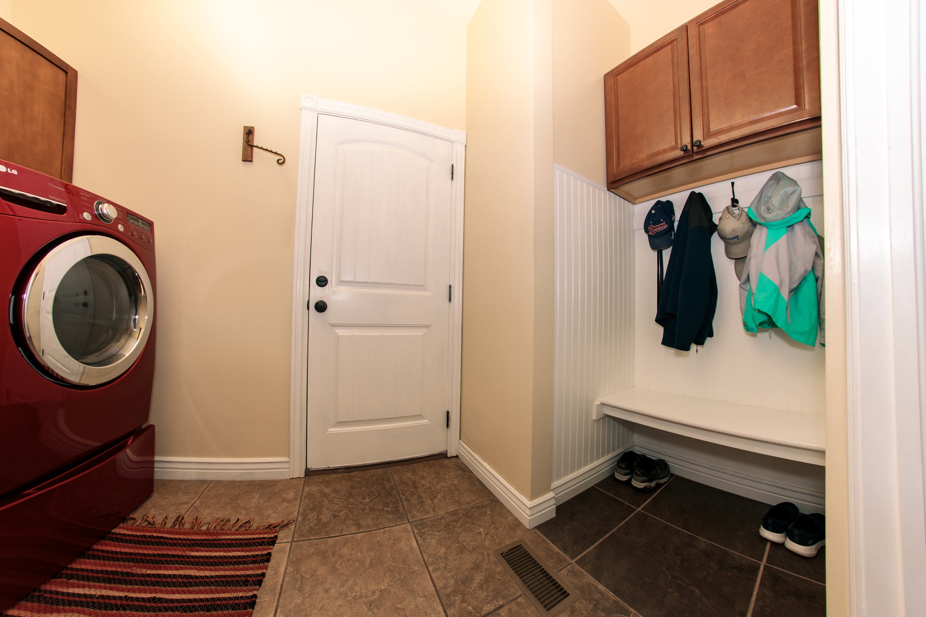 Functional mudroom featuring a built-in bench, upper cabinetry, beadboard paneling, and ceramic tile flooring