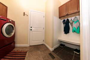 Functional mudroom featuring a built-in bench, upper cabinetry, beadboard paneling, and ceramic tile flooring